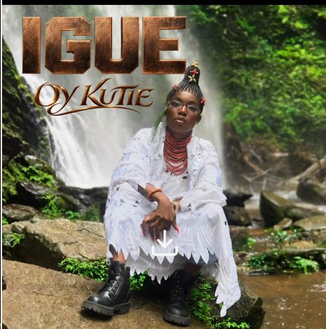 Igue cover art: OY Kutie in white lace and coral beads by a waterfall